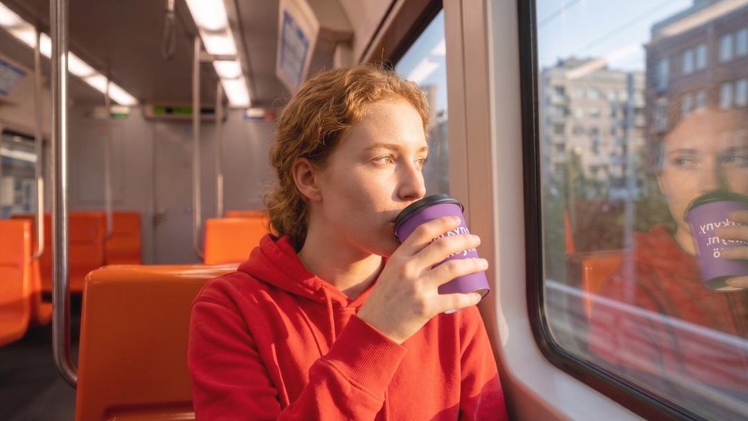 Nainen metrossa jolla muki missä lukee uskottu, toivottu, rakastettu.